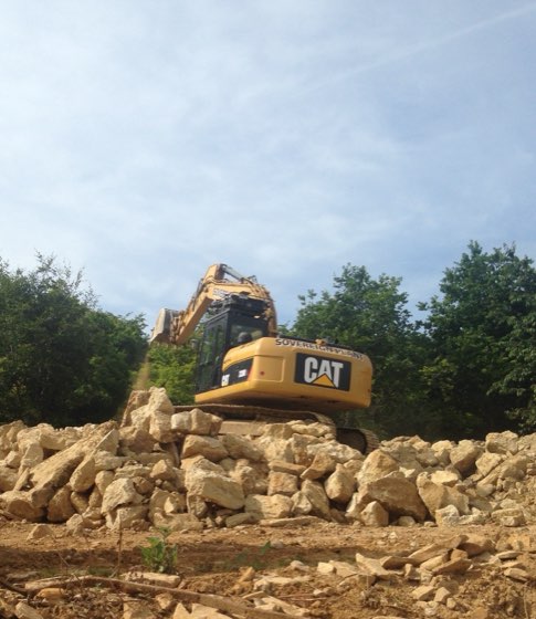 CAT digger working on a stockpile of stone