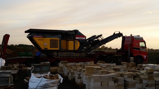 Tracked crusher on a low-loader at sunset
