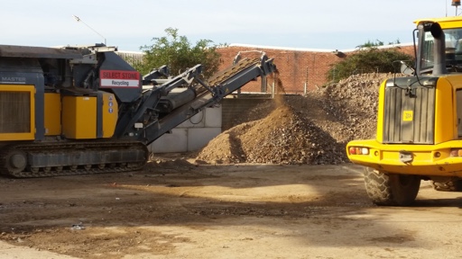 Crusher working in a recycling yard with a loading shovel