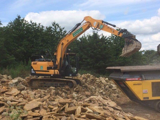 Digger loading stone into a tracked crusher